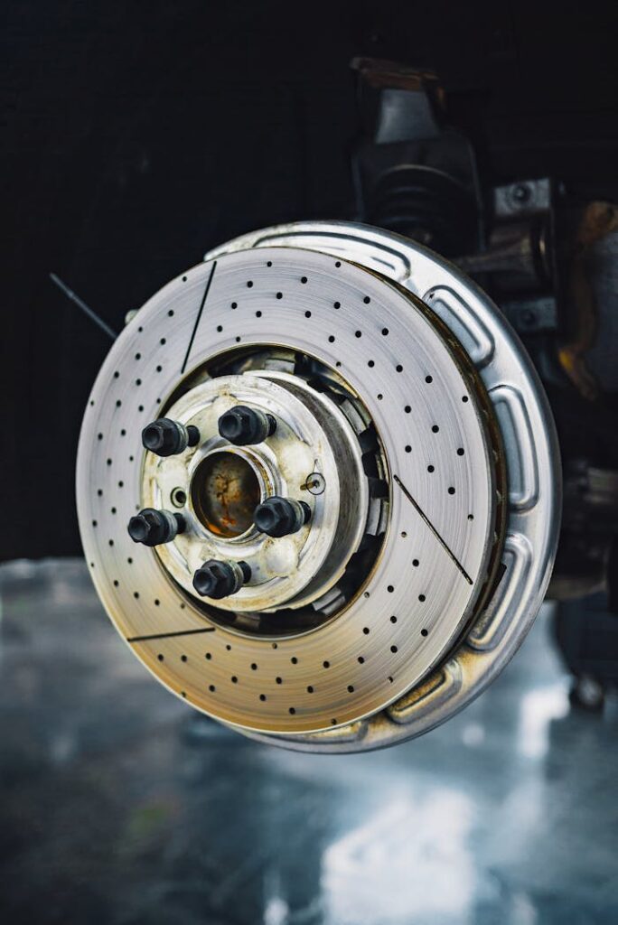 pexels-photo-4022543 Detailed view of a car brake disc, highlighting its metallic structure and components in a workshop setting.